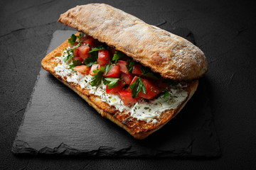 wholegraine ciabatta sandwich with sliced tomatoes, goat cheese, parsley. top view