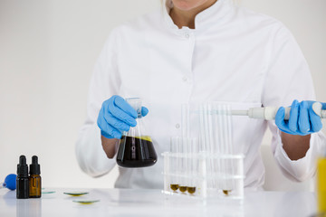 Scientist tearing the CBD oil with a precise dropper from a bowl into a tube