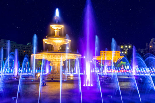 Bucharest, Romania - Fountain in Unirii Square. Fountain "Alexandru Ioan Cuza" lighted in front of the Palace of the Parliament, downtown of Bucharest, night time.