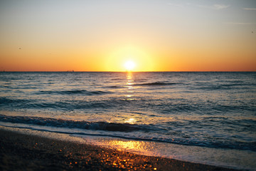 Beautiful sun rise and sea waves foam closeup at sandy beach with seashells tropical island. Waves in ocean at sunset light. Tranquil calm moment. Summer vacation. Copy space