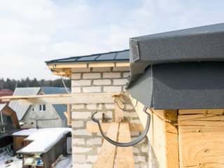 close up view of scaffolding and house under construction with holders for gutters water drainage system