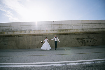 The groom in a suit and the bride in a wedding dress are on the road