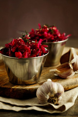Purple sauerkraut with garlic in metal bowls on a wooden board close-up.  Healthy sauerkraut salad. The concept of fermented or pickled vegetarian food