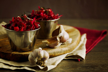Purple sauerkraut with garlic in metal bowls on a wooden board close-up copy space. Sauerkraut is fermented cabbage. The concept of fermented or pickled vegetarian food. Healthy sauerkraut salad