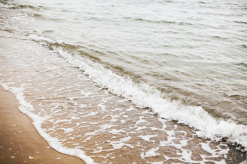 Beautiful sea waves foam closeup and sandy beach with seashells on tropical island. Waves in ocean bay or lagoon. Tranquil calm moment. Summer vacation. Copy space
