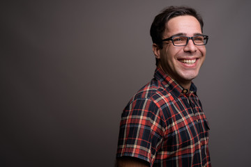 Handsome Persian man wearing eyeglasses against gray background