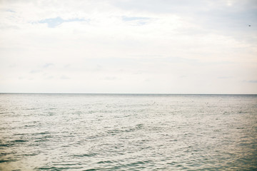 Obraz premium Piękna spokojna powierzchnia morza i niebo z chmurami na tropikalnej wyspie. Fale w zatoce oceanicznej lub lagunie. Cicha, spokojna chwila. Letnie wakacje. Skopiuj miejsce