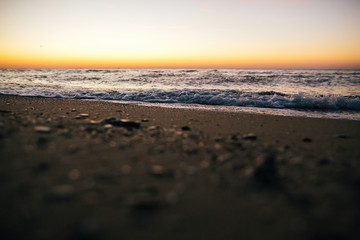 Obraz premium Beautiful sea waves foam closeup and sandy beach with seashells in sunrise light on tropical island. Waves in ocean at sunset. Tranquil calm moment. Summer vacation. Copy space