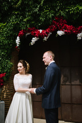 The groom in a suit and the bride in a wedding dress are standing at the wedding arch at the wedding ceremony