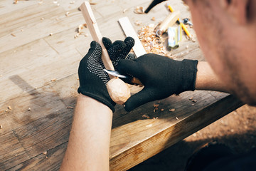 Wooden workshop. Hands carving spoon from wood, working with chisel close up. Process of making...