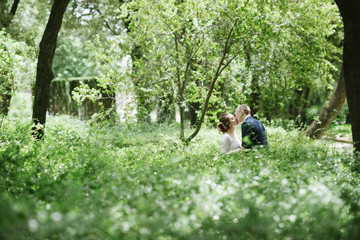 The groom in a suit and the bride in a wedding dress are walking in the park