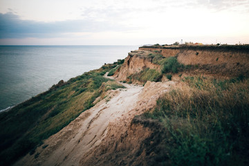 Beautiful sandy cliff  and calm sea surface, pink sky at sunset light. Beach  on tropical island at ocean bay or lagoon. Tranquil calm moment. Summer vacation. Copy space