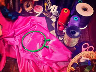 Seamstress group object sewing spool and embroidery hoop with scissors on pink textile material....