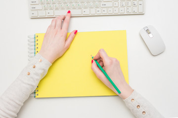 Women's hands make notes in a yellow notebook, closeup