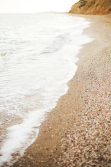 Beautiful sea waves foam closeup and sandy beach with seashells on tropical island. Waves in ocean bay or lagoon. Tranquil calm moment. Summer vacation. Copy space