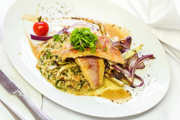 Fried fish fillet with side dish on a white plate