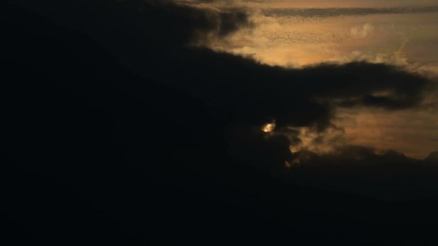 Superzoom plan timelapse sunset through sunset clouds in orange tones. Low key