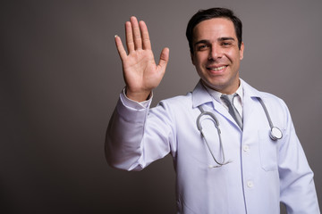 Handsome Persian man doctor against gray background