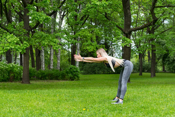 slender girl  sports in the Park, she does the forward bends