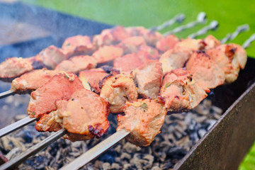pieces of meat are fried on fire on skewers