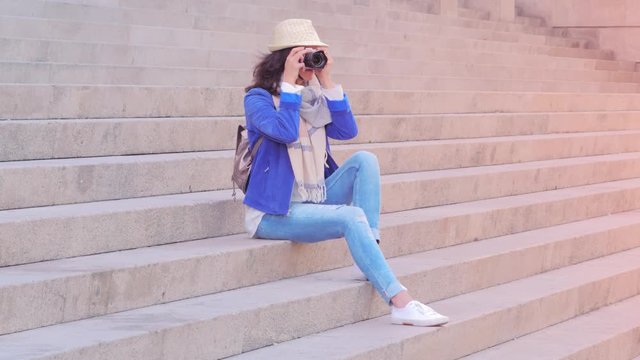 Portrait of tourist in summer holiday, on stairs taking pictures with camera.