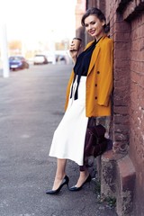 Fototapeta premium Portrait fashion woman walking on street . She wears yellow jacket, smiling to side.