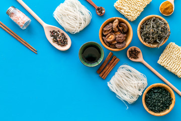 Chinese and Japanese food cooking with ginger, spices and noodles on blue background top view mock up
