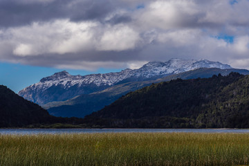 Fototapeta na wymiar Remote wild scene view of a lake against snow-capped mountains during autumn season