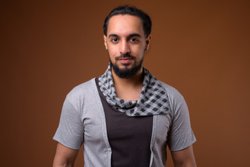 Young bearded Indian man against brown background