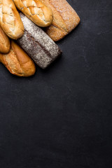 Mixed variety of breads on dark table. Top view with copy space