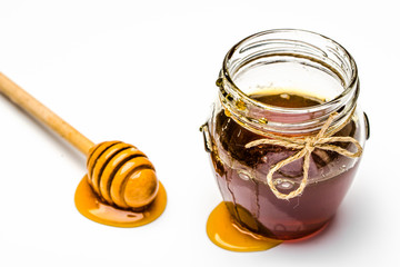 Sticky honey pot and wooden stick of honey on white background
