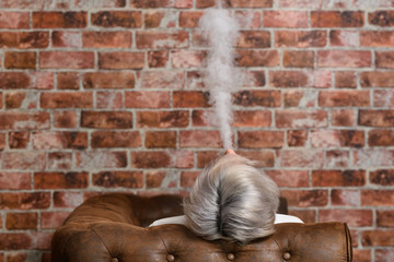 Vaper Smoke outdoor electronic cigarette near the brick wall. Young man smoking big cloud of steam