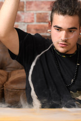 Vaper Smoke outdoor electronic cigarette near the brick wall. Young man smoking big cloud of steam