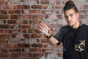 Vaper Smoke outdoor electronic cigarette near the brick wall. Young man smoking big cloud of steam