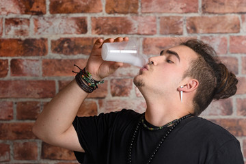 Vaper Smoke outdoor electronic cigarette near the brick wall. Young man smoking big cloud of steam