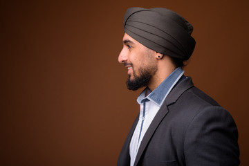 Young bearded Indian Sikh businessman wearing turban against bro