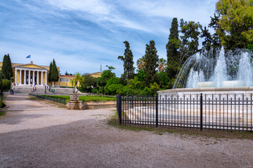 Athens City, Attica / Greece - May 20, 2019: Scenic view of the marble fountain gushing water and the Zappeion Hall neo-classical building in the National Garden park near Syntagma Square. Cloudy sky