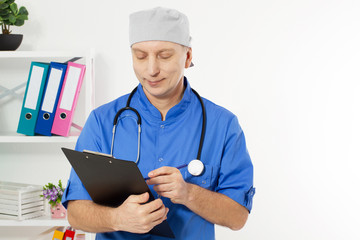 Portrait of cheerful male doctor in hospital takes notes. Surgeon with stethoscope on white background. Medical insurance Copy space.