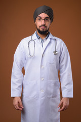Young bearded Indian Sikh man doctor wearing turban against brow