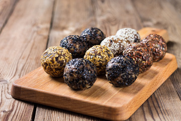 A group of energy balls lying on parchment paper on a kitchen Board. Blurred wooden background. The concept of healthy eating.