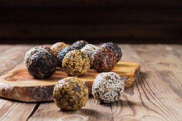 A group of energy balls lying on parchment paper on a kitchen Board. Blurred wooden background. The concept of healthy eating.