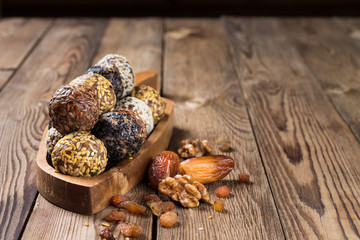 A group of energy balls lying on a wooden tray with a handle. Blurred wooden background. Organic natural food.