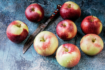 Red apples and knife on dark blue concrete background. Autumn harvest