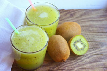 Summer refreshing drink. Healthy food, vegetarianism. Kiwi smoothie in a glass next to fresh kiwi slices on a wooden table. fruit drink.copy space