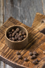 Allspice in a wooden bowl on a wooden Board. Rustic style