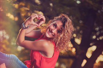 Woman holding heart shape and enjoying the sunset/sunrise.