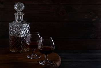 Brandy or cognac in glasses and a decanter on a brown wooden background
