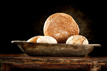 Fresh bread on wooden plate and dark wall of free space for your decoration. 