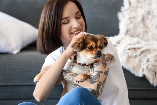 Beautiful tattooed woman with cute dog at home