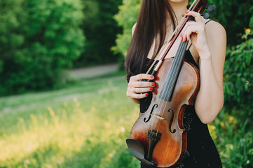 Beautiful girl holding a vintage violin in her hands. close-up